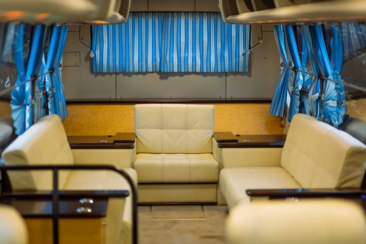 Zona de asientos tipo salón con mesas enfrentadas en el interior de un autocar de gama alta