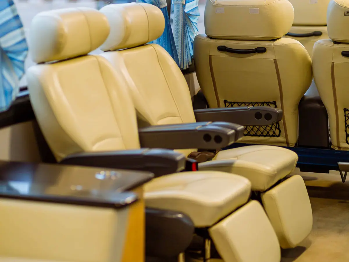 Interior de un autocar de gama alta con asientos de piel reclinables y cortinas azules